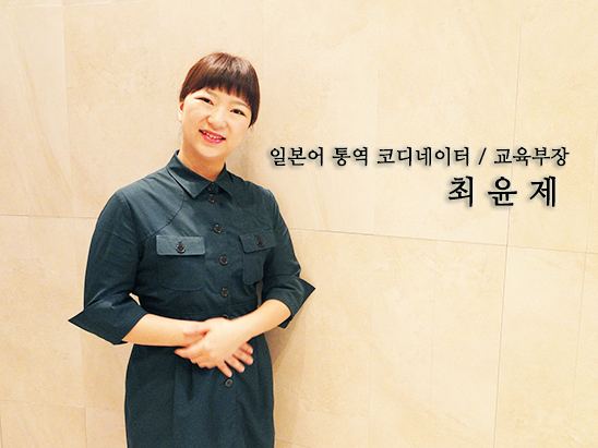 진초록색의 유니폼을 입은 여직원이 두 손을 모으고 미소짓고 있다.